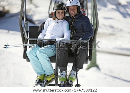 Couple riding on ski lift at resort