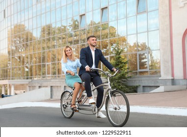 Couple Riding Tandem Bike On City Street