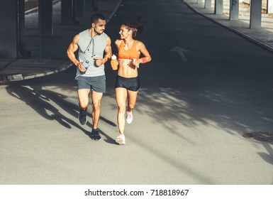 Couple of  runners jogging on the city street under the overpass.City environment. - Powered by Shutterstock