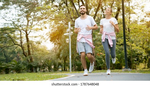 Couple Are Running Happy In The Garden. Family Workout Activity During The Holiday. Safe And Clean Exercise Places For The Health Of People Who Use The Place. Concept Sport Health