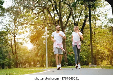 Couple Are Running Happy In The Garden. Family Workout Activity During The Holiday. Safe And Clean Exercise Places For The Health Of People Who Use The Place. Concept Sport Health