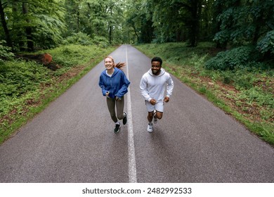 Couple running on a forest road, laughing and enjoying their workout together. They are dressed in comfortable sportswear, embracing an active lifestyle. - Powered by Shutterstock