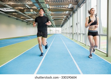 Couple Running On The Indoor Track At The Gym