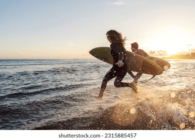 Couple is rushing to catch the waves while carrying surfboards. - Powered by Shutterstock