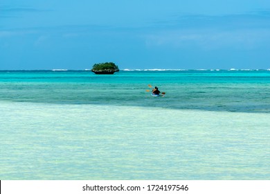 Couple Sailing On A Canoe Kayak In Tropical Beach With Palm Trees And Araucaria. Isle Of Pines New Caledonia. Turquoise Water