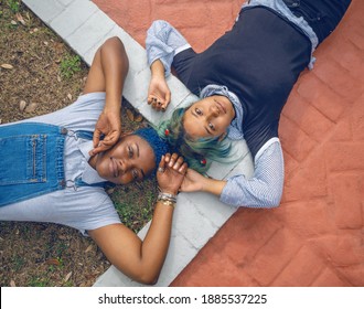 A Couple Of The Same Sex Are Lying In The Park Touching Their Hands