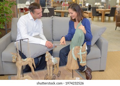 Couple Sat On Sofa In Furniture Store