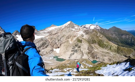 Couple With Scenic View On Hoher Sonnblick In High Tauern Mountains In Carinthia, Salzburg, Austria, Europe, Alps. Woman Leading The Way, Man Is Taking Selfies. Landscape In Hohe Tauern National Park