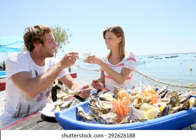 Couple In Seafood Restaurant Tasting Fresh Oysters