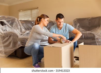 Couple Sealing Moving Boxes In Their Old Home 