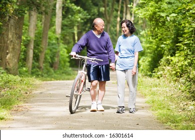 A Couple Senior Asian Talking While Walking And Exercising At A Park