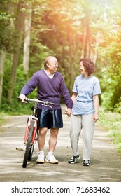 A Couple Senior Asian Talking While Walking And Exercising At A Park