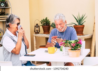 Couple Of Senior People Enjoying The Free Time Playing Cards. Background Of Plants And Old Object.