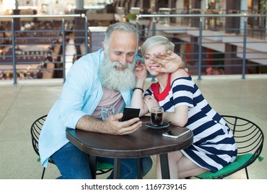 A Couple Of Senior People Are Speaking With Their Kids Using Skype Program On The Phone. She Is Waving To Her Daughter On The Screen.