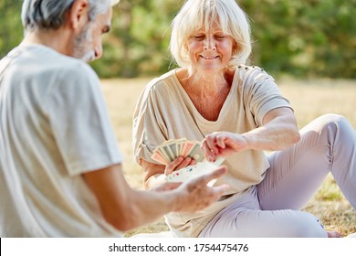 Couple Of Seniors Playing Cards Together In The Summer In The Garden