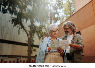 A couple of seniors are sightseeing on their vacation. They are using an old paper map to navigate around the city. - Powered by Shutterstock