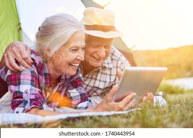 Mehrere Senioren bei Videochat mit Tablet-Computer beim Camping im Sommer