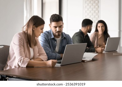 Couple of serious business colleagues sharing laptop for teamwork, meeting at computer, working on Internet startup together. Mentor training intern to use professional application - Powered by Shutterstock