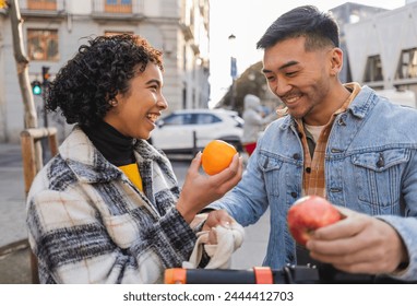 A couple shares a playful moment with fresh fruit while enjoying a city walk. - Powered by Shutterstock