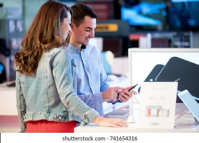 Couple Shopping For Latest Laptop And Smartphone At Tech Store