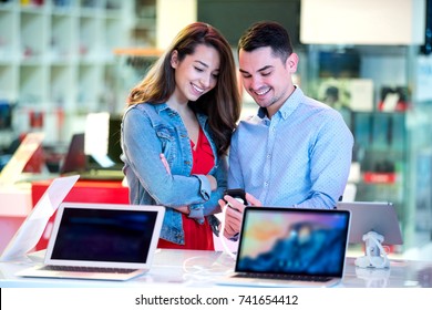 Couple Shopping For Latest Laptop And Smartphone At Tech Store