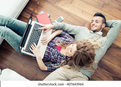 Couple shopping online at laptop computer - Two young friends watching a video on a notebook in the living room, view from above