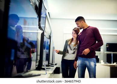 Couple In Shopping. They Are Looking For A New Tv. Shallow Depth Of Field.