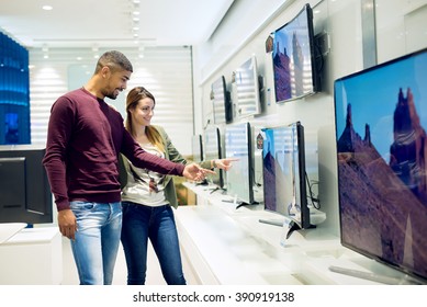 Couple in shopping. They are looking for new tv. They are pointing fingers at tv. Shallow depth of field. - Shutterstock ID 390919138