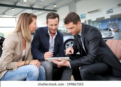 Couple Signing Car Purchase Order On Digital Tablet