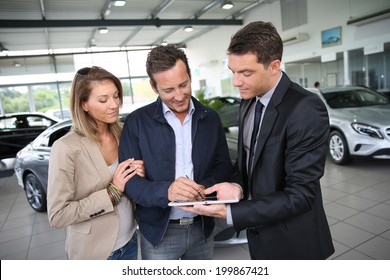 Couple Signing Car Purchase Order On Digital Tablet