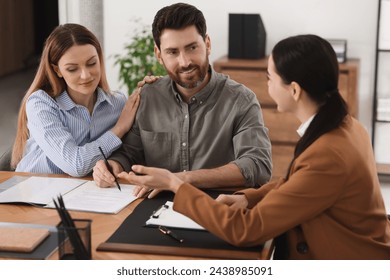 Couple signing document while having meeting with lawyer in office