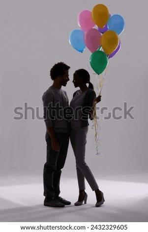 Couple, silhouette and party with balloons for celebration, event or romance on a gray studio background. Man and woman holding colorful objects of helium for art, date or anniversary on mockup space