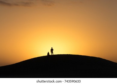 Couple silhouette watching the sunset from a sand dune in Maspalomas Gran Canaria
