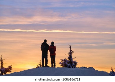 Couple silhouettes against colorful sunset sky. Snowshoeing on Cypress mountain ski resort. Vancouver. British Columbia. Canada