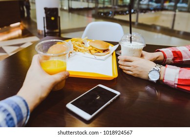 couple sit in cafe inside mall eat burgers and drink juce