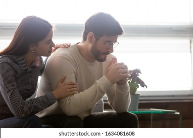 Couple sit on sofa caring wife hugs disappointed sad frustrated husband, making peace, reconcile after fight, problems in relationship, friendship and support spouses overcome problem together concept - Shutterstock ID 1634081608
