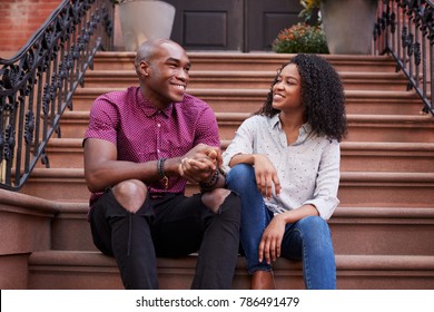 Couple Sit And Talk On Stoop Of Brownstone In New York City