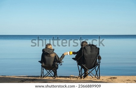 Couple sits on the folding chairs near the lake, drinks tea and enjoys relaxing in nature Foto stock © 