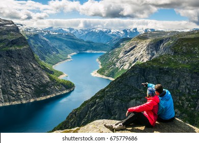 Couple sitting against amazing nature view on the way to Trolltunga. Location: Scandinavian Mountains, Norway, Stavanger. Artistic picture. Beauty world. The feeling of complete freedom