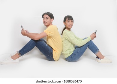 Couple Sitting Back To Back And Using Phones

