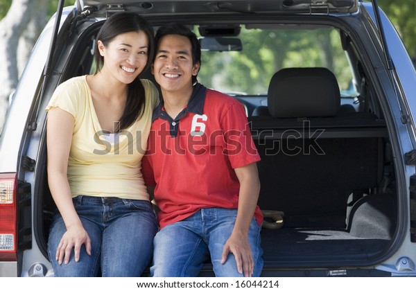 Couple sitting in back of\
van smiling