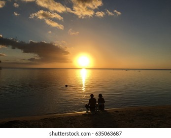 Couple Sitting At A Beach During Sunset, Moorea, French Polynesia