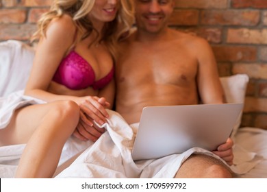 Couple sitting in bed and watching video on laptop