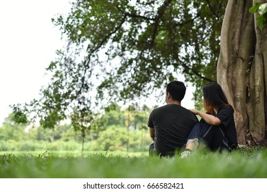 A Couple Sitting By The Big Tree Looking Far Away.