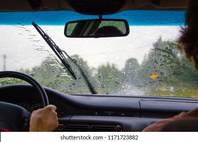 A Couple Sitting In The Car While It Is Raining Heavily. The Windshield Wipers Have A Lot To Do And Are Busy To Clear The Window View To Drive Safely