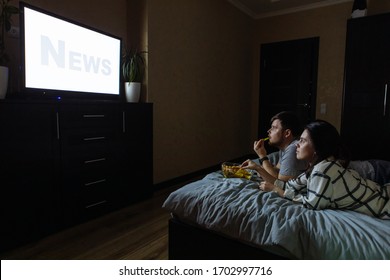 Couple Sitting In Dark Room Watching TV