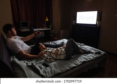 Couple Sitting In Dark Room Watching TV