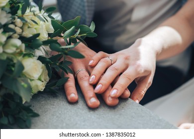 couple sitting holding hands with woman's hand on top of man's hand with wedding rings on close up