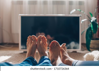 Couple sitting in home tent watching tv. Couple in love. Watch tv. Man and woman home concept. Movie. Crazy. Family photo. Holidays. Celebration. Feet. Love concept. Funny photo. Lifestyle. Life. 
