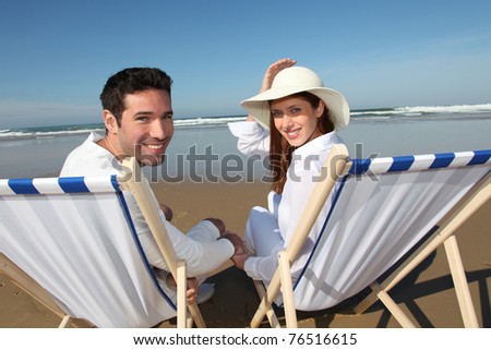 Couple sitting in longchairs at the beach